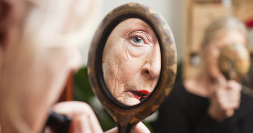Older woman looking at hand mirror