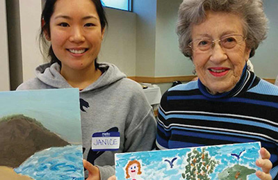 Co-ed and older woman display their paintings