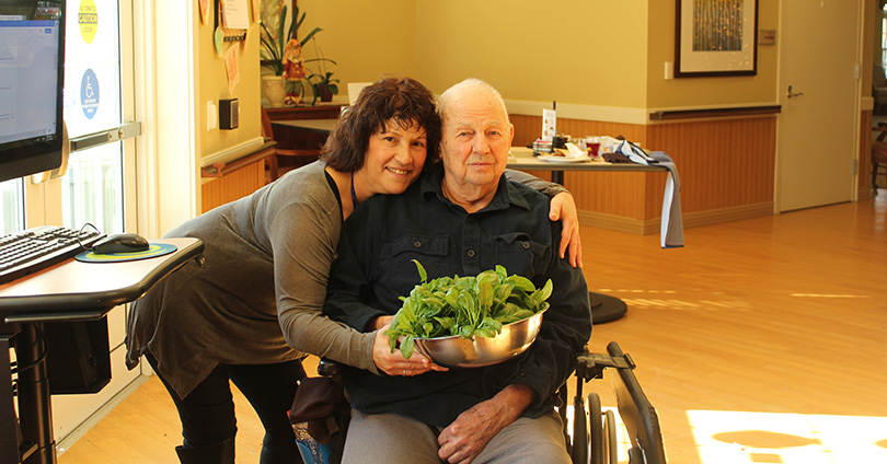 Starr and Ray holding a bowl of spinach that he harvested